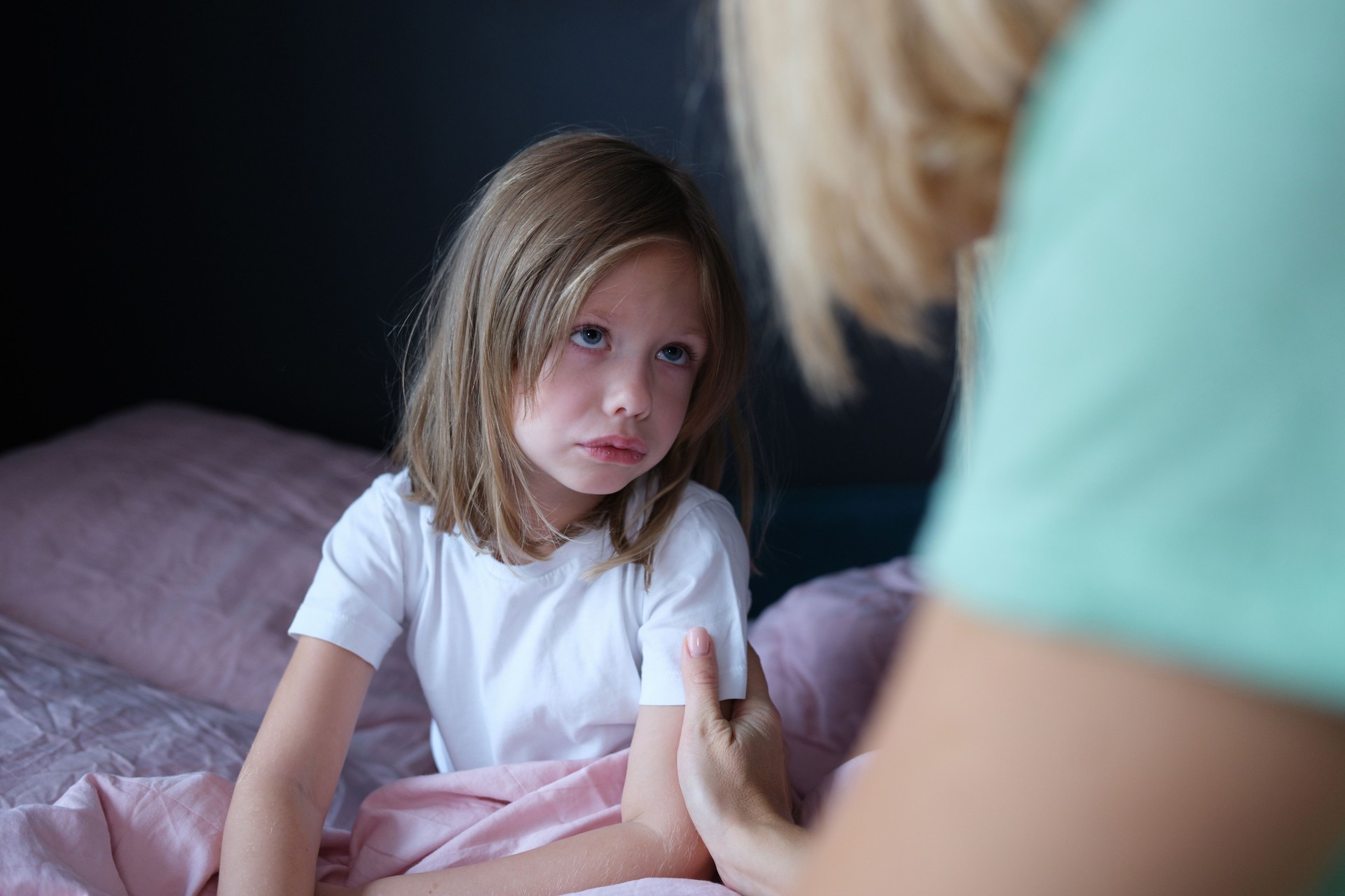 Mom calms a little girl on the bed, close-up