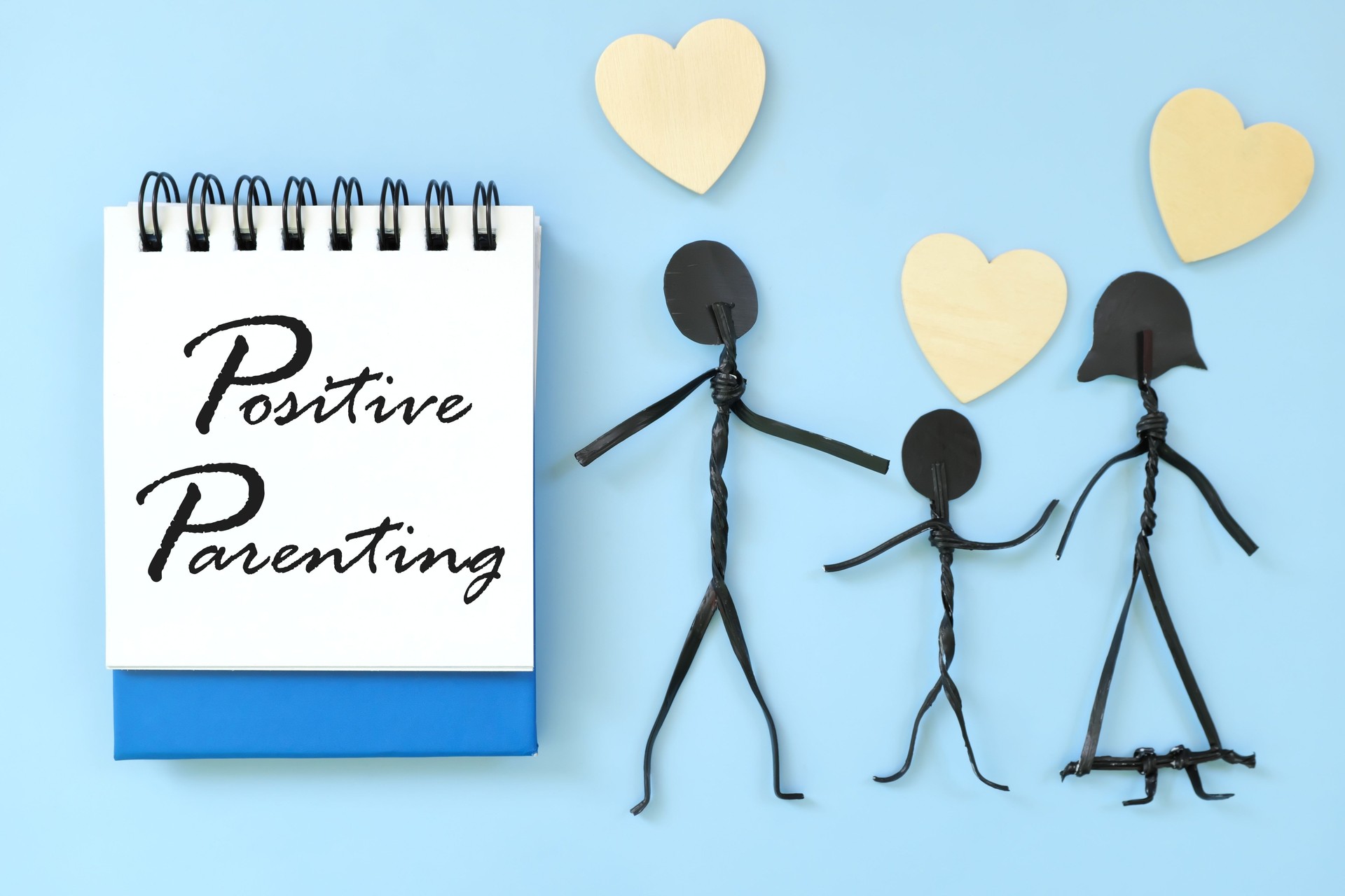 Positive parenting approach concept. Text written on blue notepad with family stick figures.