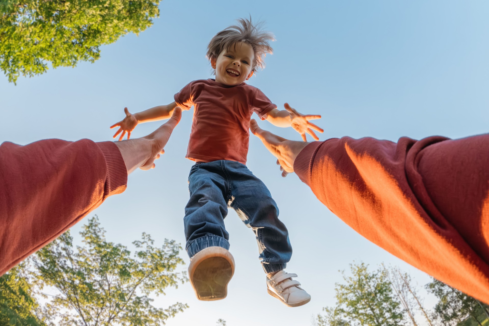 excited boy flies into his father's arms and laughs as his father tosses him up